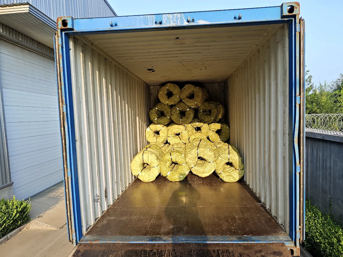wrapped razor wire coils arranged inside an open shipping container