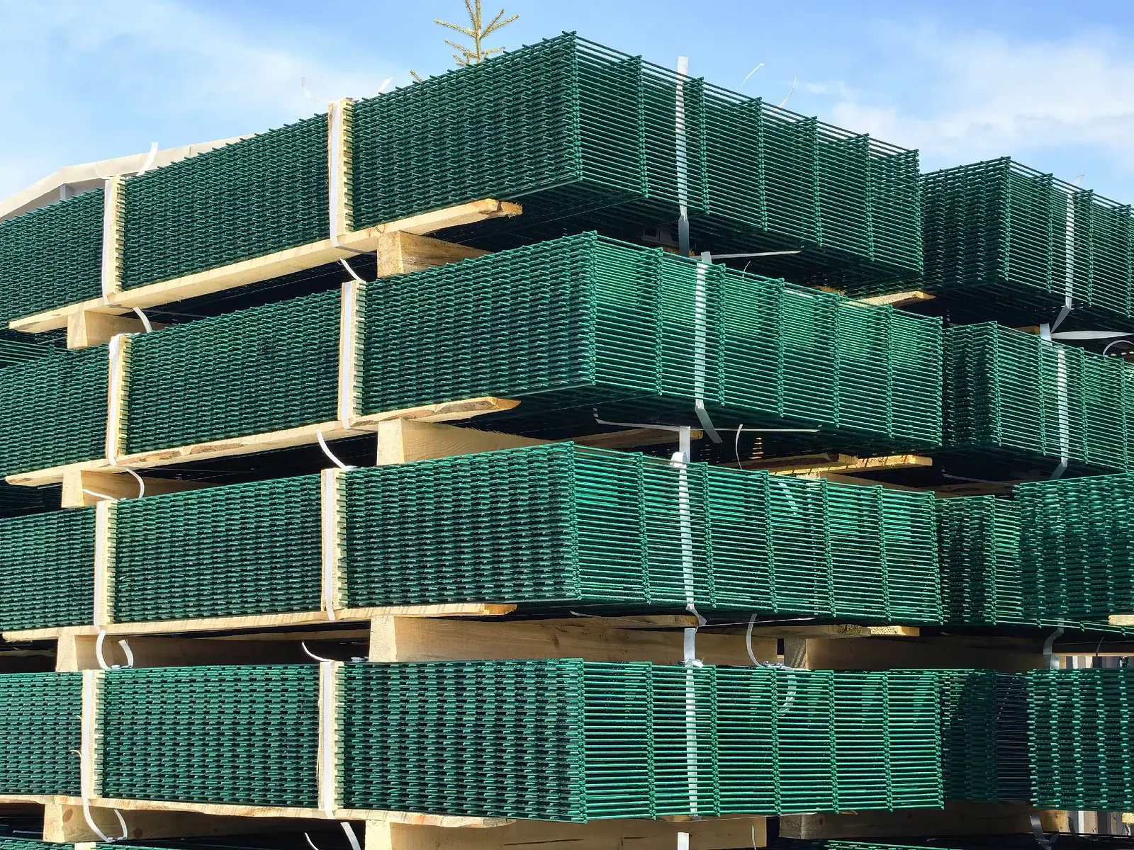 paneles verdes de cerca de malla soldada apilados con separadores de madera y flejes
