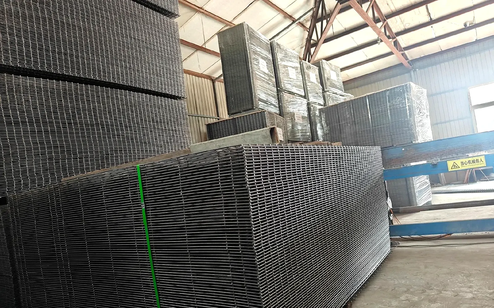 stacked welded wire fence panels stored upright inside a workshop