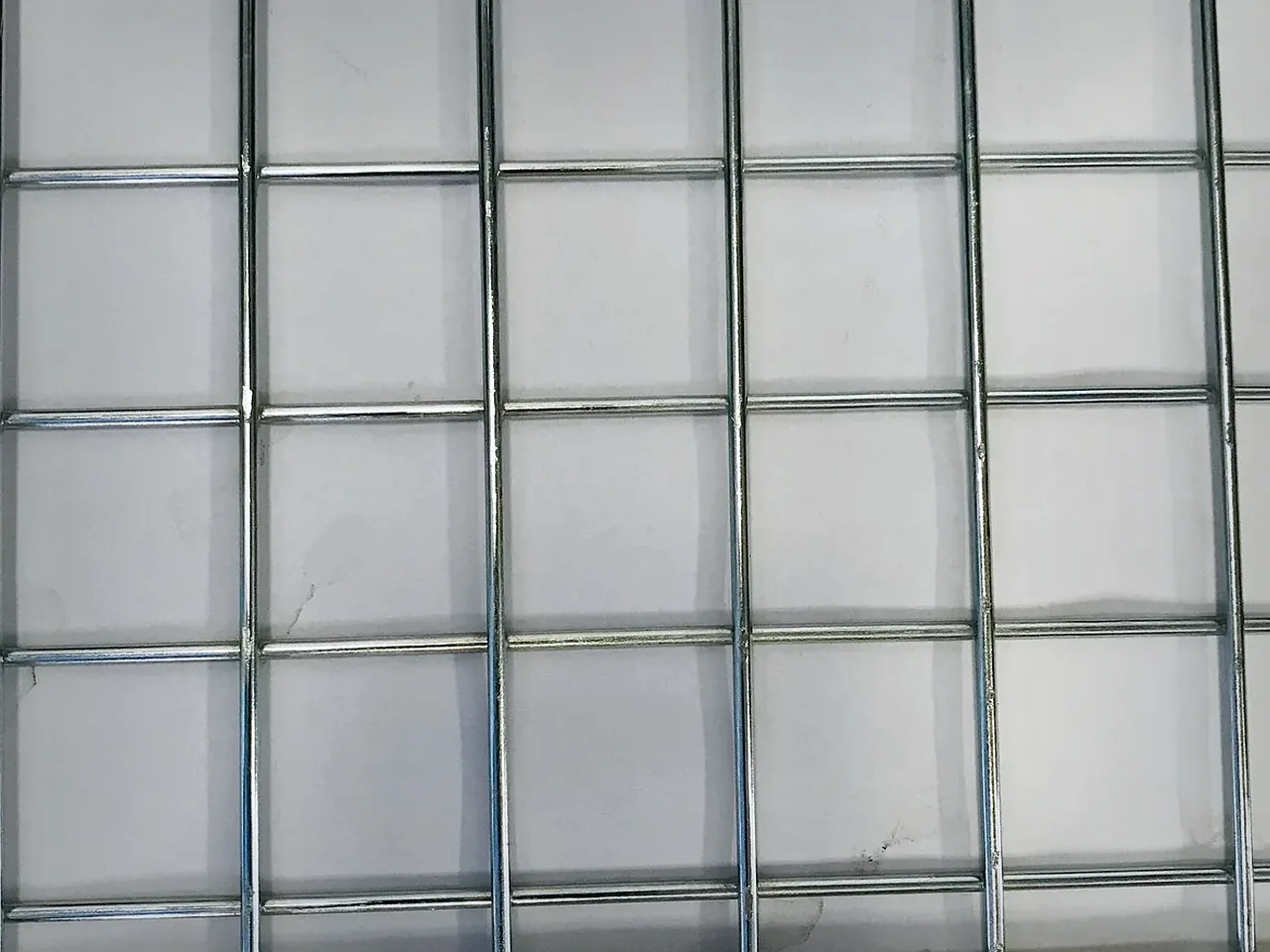 close-up of welded mesh fence wires and rigid rectangular openings