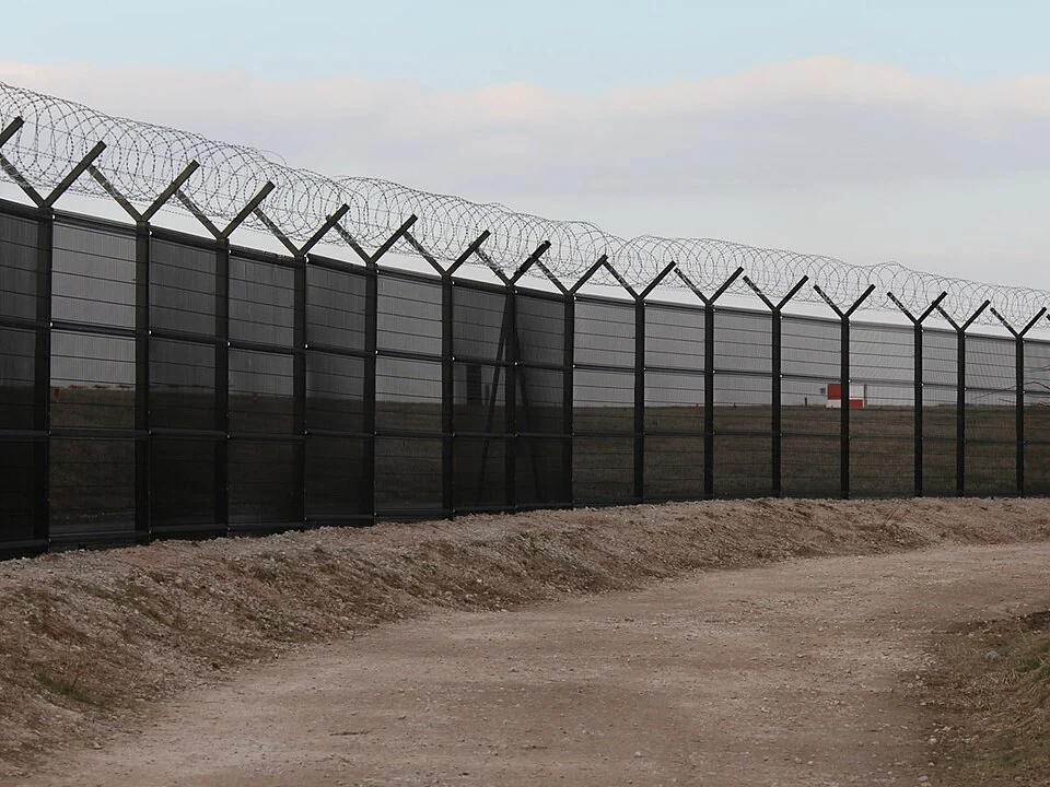 High-security rigid-mesh perimeter fence with angled posts and concertina topping