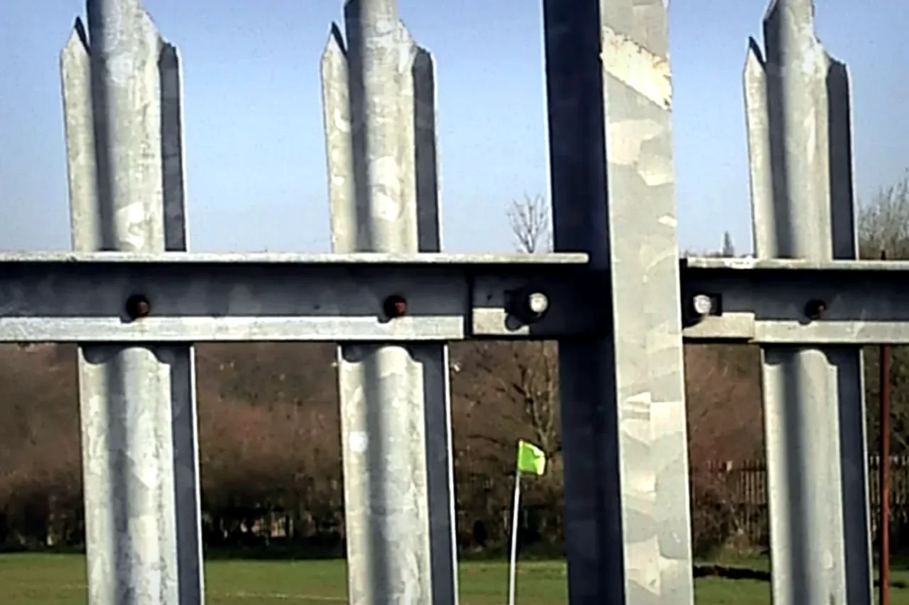 galvanized steel palisade security fence close-up with vertical pales rails and bolts